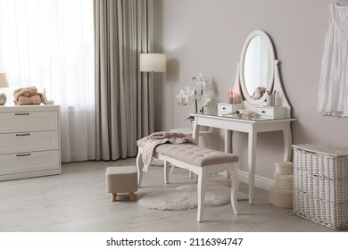 Wooden dressing table with decorative elements and makeup products in room. Interior design