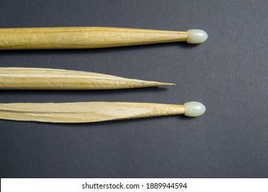 Wooden Drum Sticks On A Black Background. One Of The Sticks Is Broken