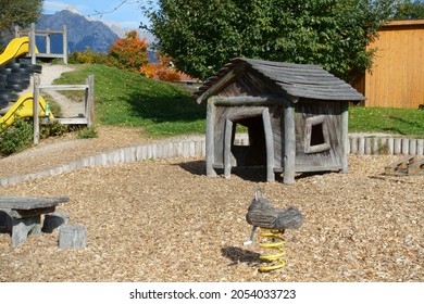 Wooden Duck Swing In Front Of Wooden Play House On Playground In Early Autumn                               