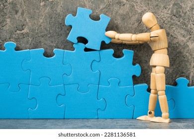 Wooden dummy building blue puzzle. Creating or building own business concept.Compliting final task. - Powered by Shutterstock