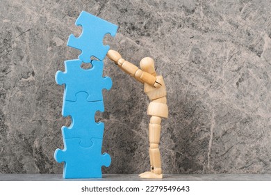 Wooden dummy building a tower from a blue puzzle. Creating or building own business concept. - Powered by Shutterstock