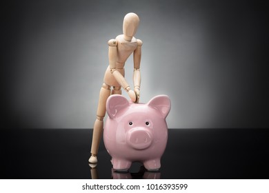 Wooden Dummy Inserting Coin In Pink Piggy Bank On Grey Background - Shutterstock ID 1016393599