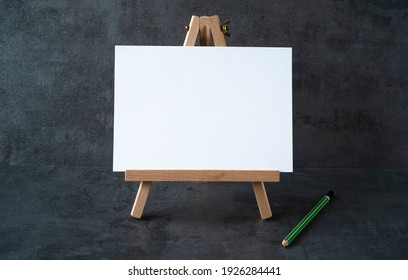 Wooden Easel With White Board With Space For Text And Green Pencil On Gray Background