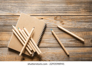 Wooden eco pencils and recycled notebook on a wooden background, top view. Eco-friendly school stationery.
