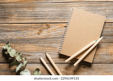 Wooden eco pencils and recycled notebook on a wooden background, top view. Eco-friendly school stationery.