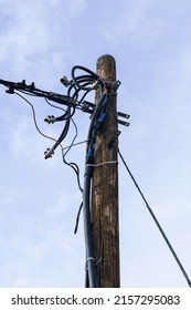 wooden electric pole with attached wires and cables on a blue sky background