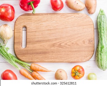 Wooden Empty Chopping Board And Vegetables Near It.