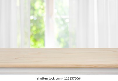 Wooden empty table in front of blurred curtained window background