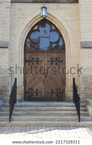 Wooden entrance to a church with steps leading up to it. Glass above door. Daytime picture in portrait orientation 