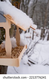 Wooden Feeder For Wild Forest Birds With Food Hanging On Tree Covered With Fresh Icy Frozen Snow And Snowflakes On Frosty Winter Day In Forest Or Garden. Animal Care. Snowy Winter Season In Nature