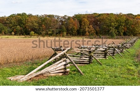 A wooden fence along a wheat field with a tree line in the distance at the Gettysburg National Military Park on a sunny fall day