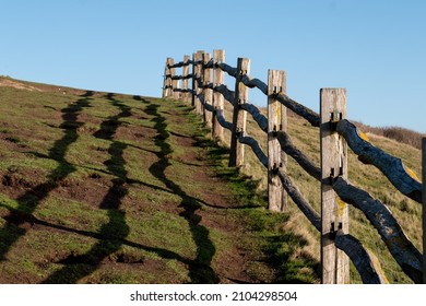 Wooden Fence At Cliff Edge, With Shadow On The Grass, Photographed At Hope Gap, Seaford, East Sussex UK