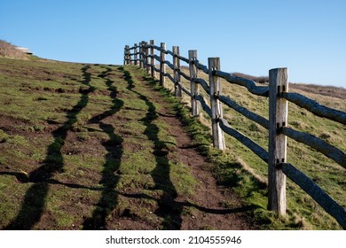 Wooden Fence At Cliff Edge, With Shadow On The Grass, Photographed At Hope Gap, Seaford, East Sussex UK