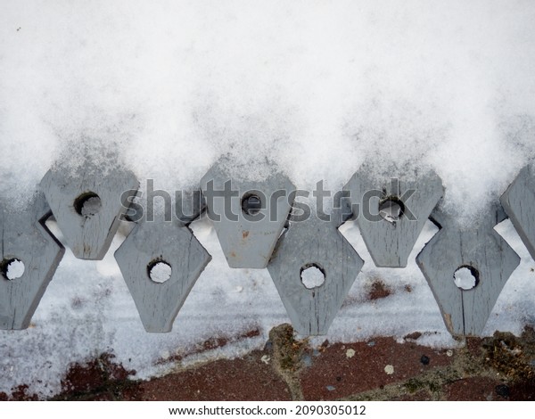 Wooden fence denticles. Items in the snow. Homemade\
fence in the snow