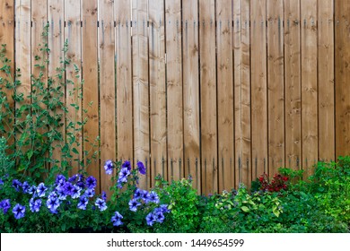 Wooden fence in a frame of green and purple flowers