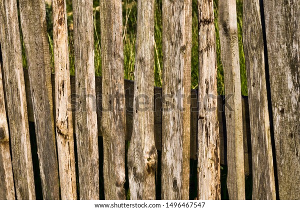 wooden fence made of planks and\
picket fence, close-up on the territory owned by different people\
and divided by the old primitive low fence, Eastern\
Europe