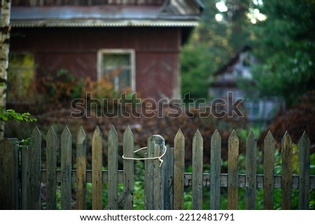 A wooden fence in an old abandoned village. Abandoned wooden houses. Residents have left for other places.