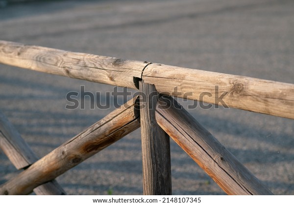wooden fence,\
particular crossing of poles to support the handrail dividing a\
cycle path with the nearby\
road.