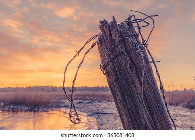 Wooden fence post with barb wire in the winter sunrise - Powered by Shutterstock