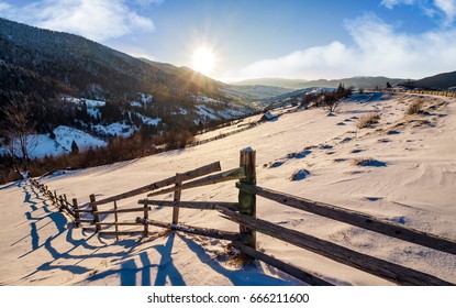 시골 지역의 나무 울타리. 눈 덮인 들판이 있는 산들의 겨울 시골 풍경. 화창한 아침 스톡 사진