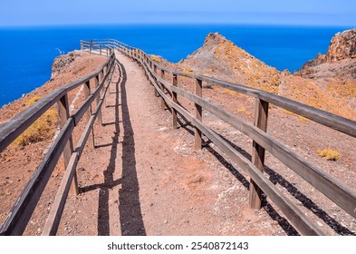 A wooden fence with a view of the ocean. The fence is long and stretches across the entire scene. The view of the ocean is breathtaking and serene - Powered by Shutterstock