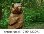 wooden figure bear in summer park, nature background. bear sculpture made of wood.