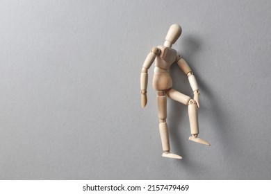 A wooden figure of a man holding his knee. Knee pain