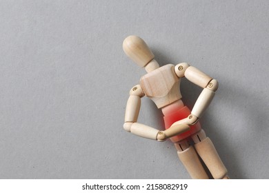 A wooden figure of a man holding his stomach. Stomach pain