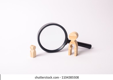 A Wooden Figure Of A Woman And A Child Stands Near The Magnifying Glass. The Concept Of Finding A Child, The Adoption Of Children. Mother Lost Her Baby And Is Now Looking For Him.