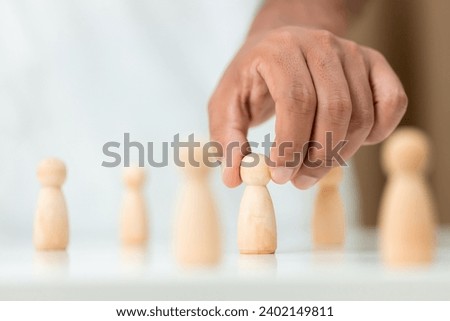 Wooden figures human was chosen leadership of teamwork. man's hands are select wooden puppet to devise strategies for appointing leaders. leadership of teamwork concept.