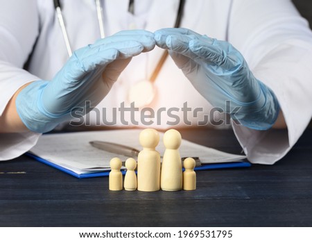 wooden figures of little men - a family, the doctor's hands cover the family for protection from diseases. Health insurance concept, doctor help