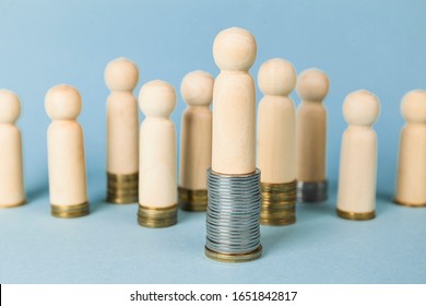 Wooden figures on stacks of coins, concept of wealth and poverty. Rising or falling wages, social inequality.