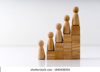 Wooden figures stand on the cubes that represent the stairs. The concept of social inequality or career growth.
