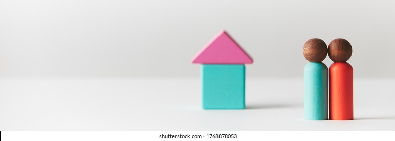 Wooden Figurines Concept. Two Wooden Figures People Standing In Front Of A Tiny Block House, Black Skin Colour, Young Couple. Realty Market. Banner