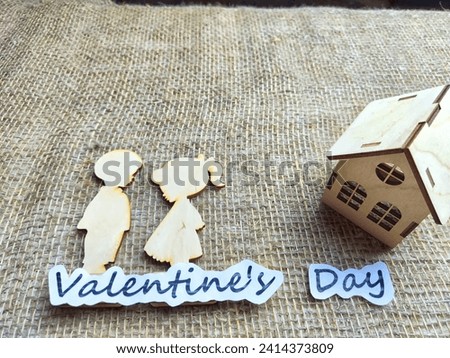 Wooden figurines of a couple, a house and the inscription Valentine's Day. The concept of a holiday of love and lovers. Background, texture, place for text and copy space