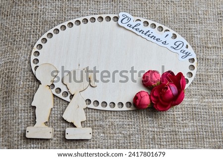 Wooden figurines of couple, inscription Valentine's Day, red flowers. Concept of holiday of love. Background, texture, frame, place for text, copy space