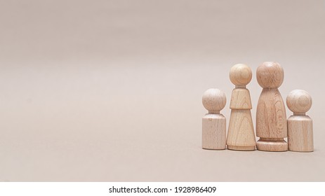 Wooden Figurines Of A Family Of 4 On A Beige Background
