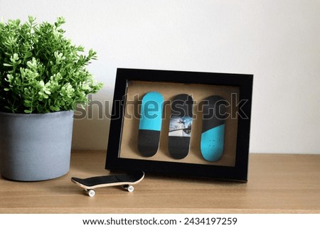 Wooden fingerboard on the table with fingerboard in the frame picture as a modern decor with flower. Mini skateboard, small skateboard deck