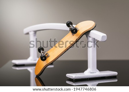 Wooden fingerboard and white metal railing for riding on small skateboards on a gray background.