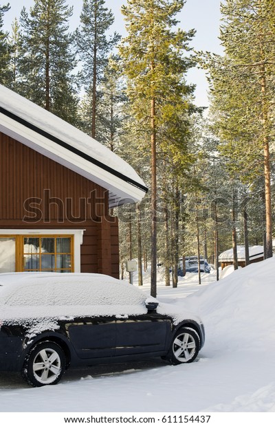 Wooden\
Finnish cottage in winter forest covered with\
snow