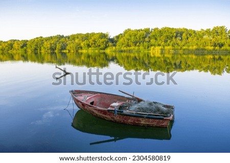 Wooden fishing boat in calm river water, Old traditional wooden boat, boat and paddle in still lake water, boat Moored Pier side River or lake, Reflection of forest and sky clouds in Calm river water