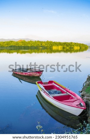 Wooden fishing boat in calm river water, Old traditional wooden boat, boat and paddle in still lake water, boat Moored Pier side River or lake, Reflection of forest and sky clouds in Calm river water