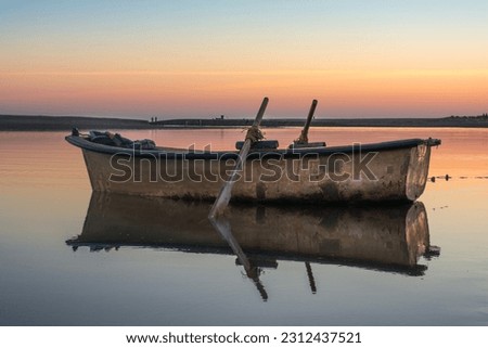 Wooden fishing boat in calm river water, Old traditional wooden boats, boat and paddle in still lake water, boat Moored Pier side River, Reflection of boat and sky sunset in Jijel a Algeria Africa.wat