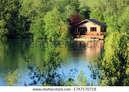 A Wooden Fishing Lodge On The Banks Of A Cotswold Leisure Lake. UK