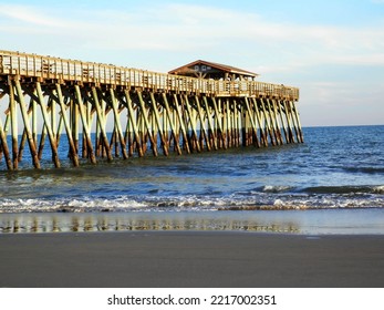 A Wooden Fishing Pier Reaches Out Into The Ocean.