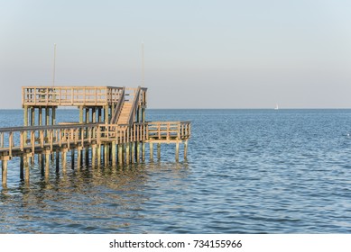 Wooden Fishing Piers Stretching Out Over Galveston Bay In Kemah, Texas, USA. Foot Pier For Saltwater Fishing Of Vacation Home/beach House Rental/bay Home In Lighthouse District Waterfront At Sunset