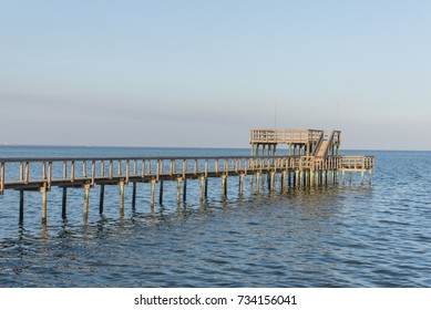 Wooden Fishing Piers Stretching Out Over Galveston Bay In Kemah, Texas, USA. Foot Pier For Saltwater Fishing Of Vacation Home/beach House Rental/bay Home In Lighthouse District Waterfront At Sunset