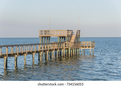 Wooden Fishing Piers Stretching Out Over Galveston Bay In Kemah, Texas, USA. Foot Pier For Saltwater Fishing Of Vacation Home/beach House Rental/bay Home In Lighthouse District Waterfront At Sunset