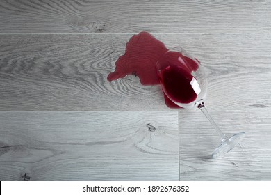 Wooden floor with overturned glass of red wine. Spilled wine on a wooden laminate (parquet) floor with moisture protection.