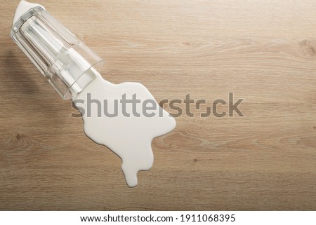 Wooden floor with overturned glass of white milk. Spilled  white milk on a wooden laminate (parquet) floor with moisture protection.	